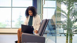 Woman typing on laptop, sitting in a chair